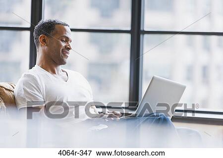 Man using laptop in loft apartment View Large Photo Image Stock Photo - Man using laptop in loft apartment. Fotosearch