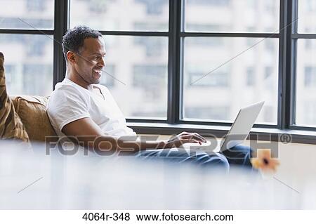 Man using laptop in loft apartment View Large Photo Image Stock Photo - Man using laptop in loft apartment. Fotosearch