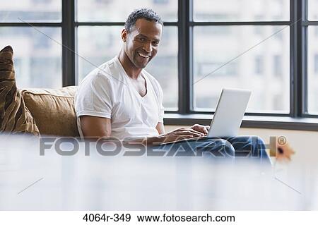Man using laptop in loft apartment View Large Photo Image Stock Photo - Man using laptop in loft apartment. Fotosearch