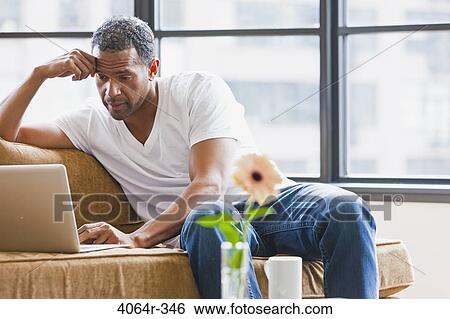 Man using laptop in loft apartment View Large Photo Image Stock Photograph - Man using laptop in loft apartment. Fotosearch