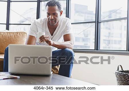 Man using laptop in loft apartment View Large Photo Image Stock Photography - Man using laptop in loft apartment. Fotosearch