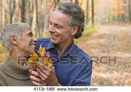 Mature couple holding Autumn leaves in forest View Large Photo Image Stock Image - Mature couple holding Autumn leaves in forest. Fotosearch