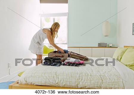 Stock Photograph - Mature woman packing suitcase. Fotosearch