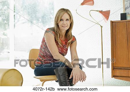 Mature woman sitting on a chair and smiling View Large Photo Image Stock Image - Mature woman sitting on a chair and smiling. Fotosearch
