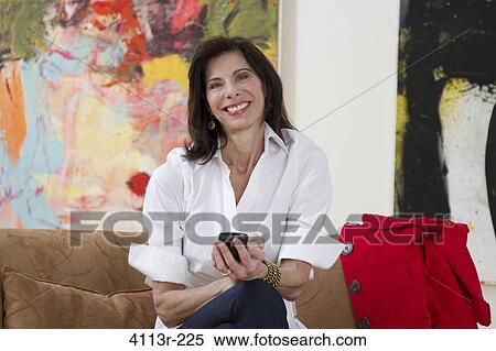 Mature woman sitting on sofa and text messaging in art gallery View Large Photo Image Stock Photography - Mature woman sitting on sofa and text messaging in art gallery. Fotosearch