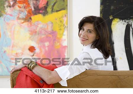 Mature woman sitting on sofa in art gallery View Large Photo Image Stock Photo - Mature woman sitting on sofa in art gallery. Fotosearch