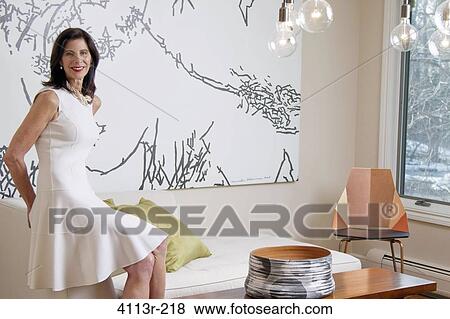 Stock Photo - Mature woman sitting on sofa in art gallery. Fotosearch