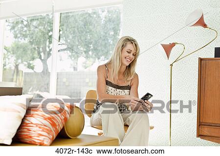 Stock Image - Mature woman text messaging and smiling. Fotosearch