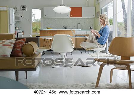 Stock Image - Mature woman text messaging at home. Fotosearch