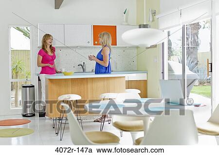 Mature woman with her friend standing in the kitchen View Large Photo Image Stock Image - Mature woman with her friend standing in the kitchen. Fotosearch