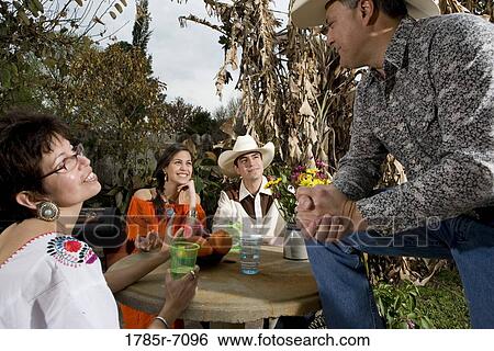 Mexican-American family sitting around a table conversing in backyard View Large Photo Image Stock Photograph - Mexican-American family sitting around a table conversing in backyard. Fotosearch