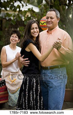 Mexican-American man dancing with his daughter while his wife claps in the background View Large Photo Image Stock Image - Mexican-American man dancing with his daughter while his wife claps in the background. Fotosearch