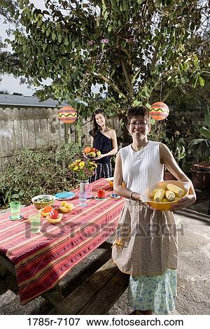 Stock Photo - Mexican-American mother and daughter setting a picnic table. Fotosearch