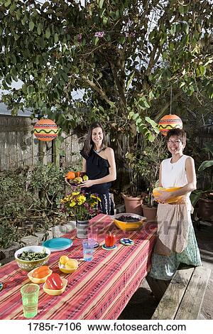 Stock Photograph - Mexican-American mother and daughter setting a picnic table. Fotosearch