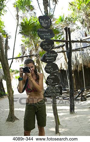 Mexico, Quintana Roo, Tulum, Female tourist taking photograph by directional sign at resort View Large Photo Image Picture - Mexico, Quintana Roo, Tulum, Female tourist taking photograph by directional sign at resort. Fotosearch
