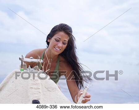 Stock Photograph - Mexico, Quintana Roo, Tulum, Young woman making sand castle on beach. Fotosearch