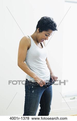 Mid adult woman holding out waistband of jeans View Large Photo Image Stock Photo - Mid adult woman holding out waistband of jeans. Fotosearch