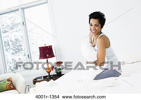 Mid adult woman hugging a pillow on the bed View Large Photo Image Picture - Mid adult woman hugging a pillow on the bed. Fotosearch