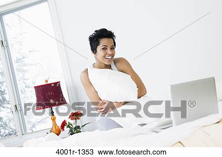 Mid adult woman hugging a pillow on the bed View Large Photo Image Stock Image - Mid adult woman hugging a pillow on the bed. Fotosearch