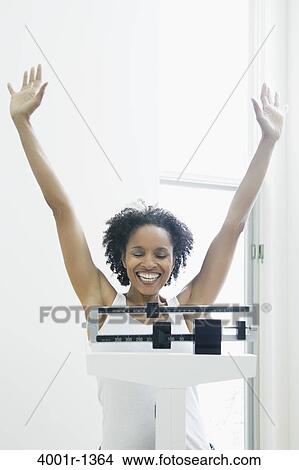 Mid adult woman measuring her weight on a weighing scale View Large Photo Image Picture - Mid adult woman measuring her weight on a weighing scale. Fotosearch