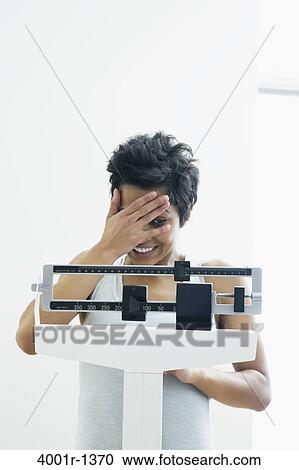Mid adult woman measuring her weight on a weighing scale View Large Photo Image Stock Image - Mid adult woman measuring her weight on a weighing scale. Fotosearch
