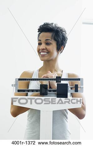 Mid adult woman measuring her weight on a weighing scale View Large Photo Image Stock Image - Mid adult woman measuring her weight on a weighing scale. Fotosearch