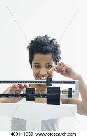 Mid adult woman measuring her weight on a weighing scale View Large Photo Image Stock Photo - Mid adult woman measuring her weight on a weighing scale. Fotosearch