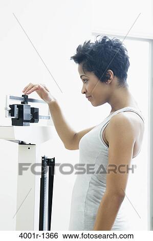 Mid adult woman measuring her weight on a weighing scale View Large Photo Image Stock Photograph - Mid adult woman measuring her weight on a weighing scale. Fotosearch