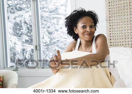 Picture - Mid adult woman sitting on the bed and smiling. Fotosearch