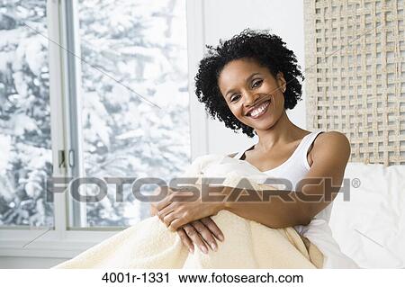 Mid adult woman sitting on the bed and smiling View Large Photo Image Stock Image - Mid adult woman sitting on the bed and smiling. Fotosearch