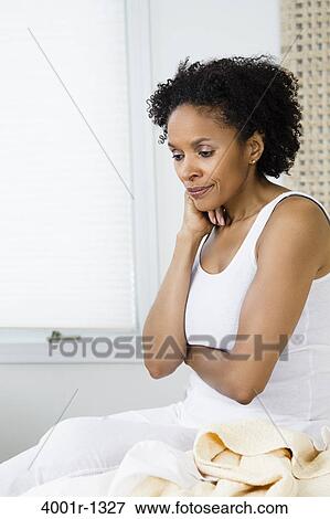 Mid adult woman sitting on the bed and thinking View Large Photo Image Stock Photo - Mid adult woman sitting on the bed and thinking. Fotosearch