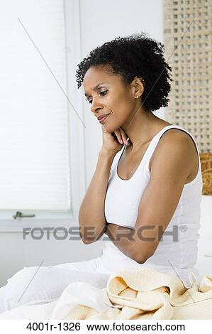 Mid adult woman sitting on the bed and thinking View Large Photo Image Stock Photograph - Mid adult woman sitting on the bed and thinking. Fotosearch