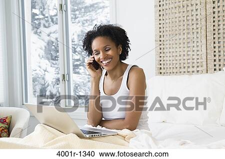 Mid adult woman using a laptop and talking on a mobile phone View Large Photo Image Stock Image - Mid adult woman using a laptop and talking on a mobile phone. Fotosearch