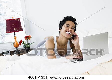 Mid adult woman using a laptop and talking on a mobile phone View Large Photo Image Stock Image - Mid adult woman using a laptop and talking on a mobile phone. Fotosearch
