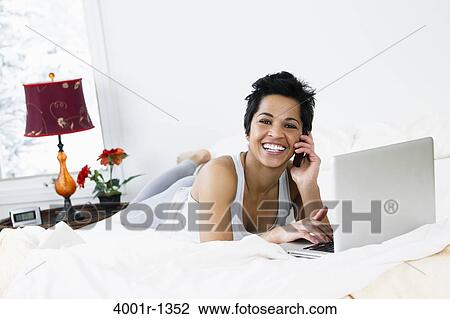 Mid adult woman using a laptop and talking on a mobile phone View Large Photo Image Stock Image - Mid adult woman using a laptop and talking on a mobile phone. Fotosearch