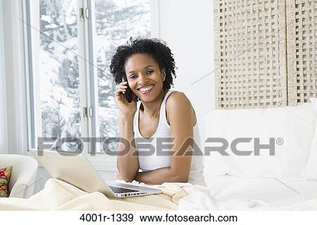 Mid adult woman using a laptop and talking on a mobile phone View Large Photo Image Stock Photo - Mid adult woman using a laptop and talking on a mobile phone. Fotosearch