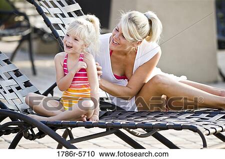 Stock Image - Mother and daughter having fun on lounge chairs. Fotosearch