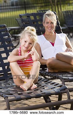 Mother and daughter relaxing on pool lounge chairs View Large Photo Image Stock Image - Mother and daughter relaxing on pool lounge chairs. Fotosearch