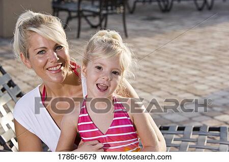 Mother and daughter relaxing on pool lounge chairs View Large Photo Image Stock Photo - Mother and daughter relaxing on pool lounge chairs. Fotosearch
