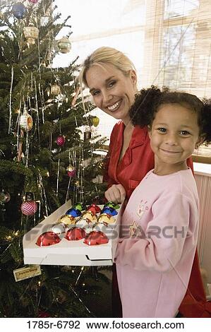 Mother with daughter in pajamas decorating Christmas tree View Large Photo Image Stock Image - Mother with daughter in pajamas decorating Christmas tree. Fotosearch