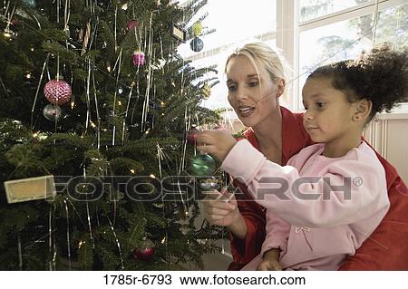 Mother with daughter in pajamas decorating Christmas tree View Large Photo Image Stock Image - Mother with daughter in pajamas decorating Christmas tree. Fotosearch