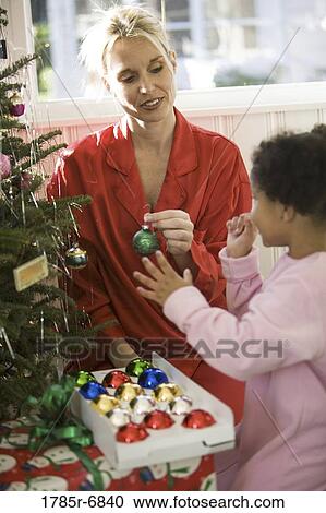 Mother with daughter in pajamas decorating Christmas tree View Large Photo Image Stock Image - Mother with daughter in pajamas decorating Christmas tree. Fotosearch