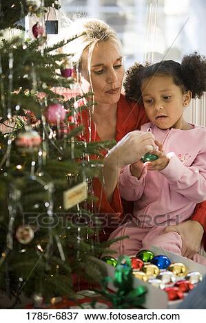 Mother with daughter in pajamas decorating Christmas tree View Large Photo Image Stock Photo - Mother with daughter in pajamas decorating Christmas tree. Fotosearch
