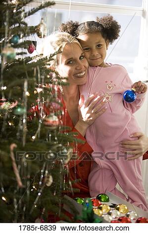 Mother with daughter in pajamas decorating Christmas tree View Large Photo Image Stock Photo - Mother with daughter in pajamas decorating Christmas tree. Fotosearch