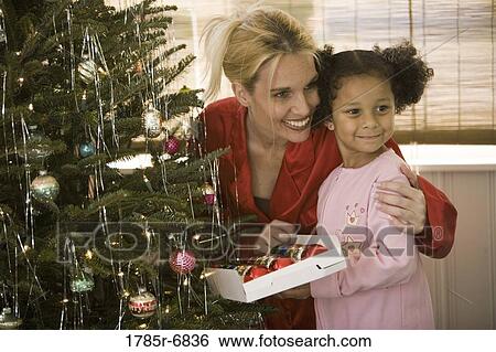 Mother with daughter in pajamas decorating Christmas tree View Large Photo Image Stock Photograph - Mother with daughter in pajamas decorating Christmas tree. Fotosearch