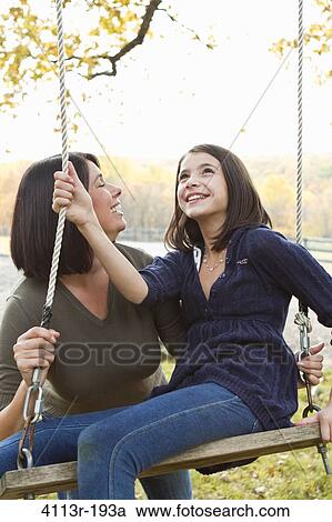 Stock Image - Mother with daughter on swing. Fotosearch