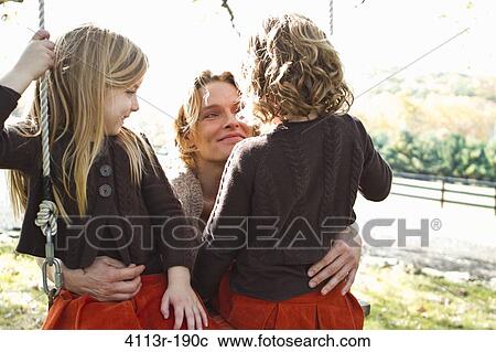 Stock Image - Mother with two daughters on swing. Fotosearch