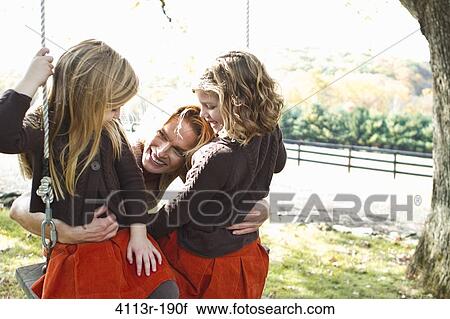 Mother with two daughters on swing View Large Photo Image Stock Image - Mother with two daughters on swing. Fotosearch