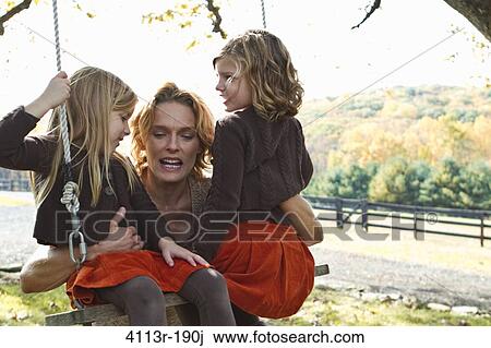 Stock Image - Mother with two daughters on swing. Fotosearch