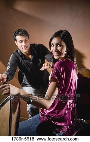 Stock Photo - Multiracial couple sitting on bar stools chatting. Fotosearch